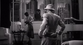 Movie still from “The Purple Rose of Cairo” (1985), directed by Woody Allen – A man and a woman in a room with a city skyline in the background; Wide shot, Low angle