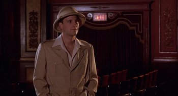 Movie still from “The Purple Rose of Cairo” (1985), directed by Woody Allen – A man wearing a hat and a jacket in front of a stage; Medium shot, Low angle