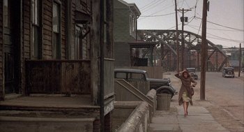 Movie still from “The Purple Rose of Cairo” (1985), directed by Woody Allen – A woman walking down the sidewalk of an alley; Wide shot, High angle