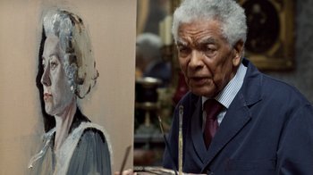 Movie still from “The Queen” (2006), directed by Stephen Frears – An older man is holding a painting of a woman; Close Up shot, Over the shoulder angle