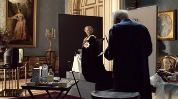 Movie still from “The Queen” (2006), directed by Stephen Frears – A man standing in front of a painting of a woman; Wide shot, High angle