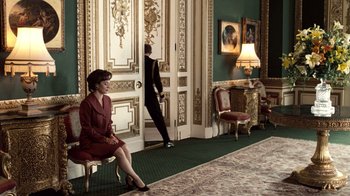 Movie still from “The Queen” (2006), directed by Stephen Frears – A woman sitting on a chair next to a man in front of a door; Wide shot, High angle