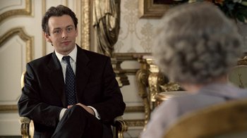 Movie still from “The Queen” (2006), directed by Stephen Frears – A man in a suit sitting in front of an older woman; Medium shot, Over the shoulder angle