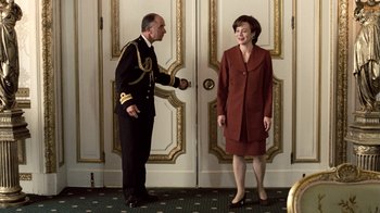 Movie still from “The Queen” (2006), directed by Stephen Frears – A man and a woman standing next to each other in front of a door; Medium shot, Low angle