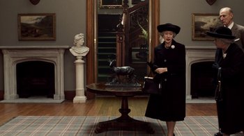 Movie still from “The Queen” (2006), directed by Stephen Frears – An older woman holding a purse in front of a statue; Wide shot, Low angle