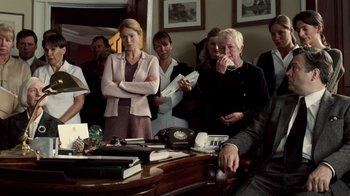 Movie still from “The Queen” (2006), directed by Stephen Frears – A group of people standing around a table; Medium shot, Over the shoulder angle