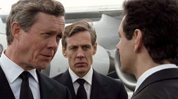 Movie still from “The Queen” (2006), directed by Stephen Frears – A group of men standing next to each other in front of an airplane; Close Up shot, Over the shoulder angle