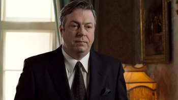 Movie still from “The Queen” (2006), directed by Stephen Frears – A person wearing a suit and tie; Close Up shot, Low angle