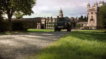 Movie still from “The Queen” (2006), directed by Stephen Frears – A car driving down a road in front of a building; Extreme Wide shot, High angle