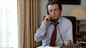 Movie still from “The Queen” (2006), directed by Stephen Frears – A man sitting at a table talking on a phone; Close Up shot, Low angle
