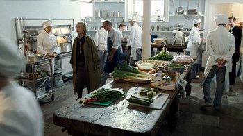 Movie still from “The Queen” (2006), directed by Stephen Frears – A group of people standing around a table in a kitchen; Wide shot, High angle