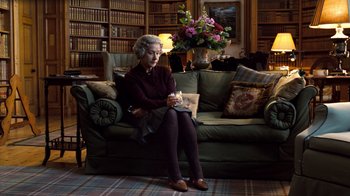 Movie still from “The Queen” (2006), directed by Stephen Frears – An older woman sitting on a couch holding a candle; Wide shot, High angle