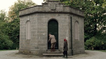 Movie still from “The Queen” (2006), directed by Stephen Frears – A man and a woman entering a stone building; Wide shot, Low angle