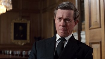 Movie still from “The Queen” (2006), directed by Stephen Frears – An older man in a suit and tie looking at the camera; Close Up shot, Over the shoulder angle