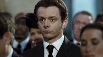 Movie still from “The Queen” (2006), directed by Stephen Frears – A person wearing a suit and tie; Close Up shot, Over the shoulder angle