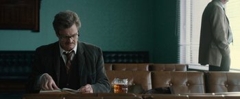 Movie still from “The Railway Man” (2013), directed by Jonathan Teplitzky – A man sitting at a table with a glass of whiskey; Medium shot, Low angle