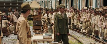 Movie still from “The Railway Man” (2013), directed by Jonathan Teplitzky – A group of men standing next to each other on a train track; Wide shot, Over the shoulder angle