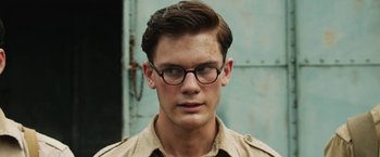 Movie still from “The Railway Man” (2013), directed by Jonathan Teplitzky – A young man wearing glasses and a tan shirt; Close Up shot, Over the shoulder angle