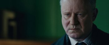 Movie still from “The Railway Man” (2013), directed by Jonathan Teplitzky – An older man in a suit and tie looking at the camera; Close Up shot, Over the shoulder angle