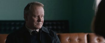 Movie still from “The Railway Man” (2013), directed by Jonathan Teplitzky – An older man sitting in a chair in a room; Close Up shot, Over the shoulder angle