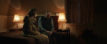 Movie still from “The Railway Man” (2013), directed by Jonathan Teplitzky – A man and a woman sitting on a couch in front of a lamp; Medium shot, Over the shoulder angle