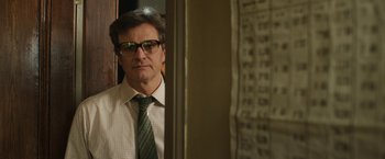 Movie still from “The Railway Man” (2013), directed by Jonathan Teplitzky – A man wearing a tie and glasses in a room; Close Up shot, Over the shoulder angle