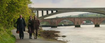 Movie still from “The Railway Man” (2013), directed by Jonathan Teplitzky – A man and a woman are standing on the side of a river; Wide shot, Over the shoulder angle