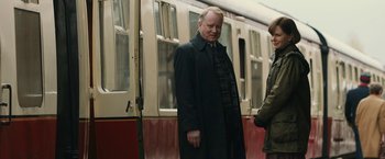 Movie still from “The Railway Man” (2013), directed by Jonathan Teplitzky – A man standing next to another man on a train platform; Medium shot, Over the shoulder angle