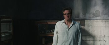 Movie still from “The Railway Man” (2013), directed by Jonathan Teplitzky – A man standing in front of a shelf in a room; Medium shot, Low angle