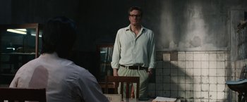 Movie still from “The Railway Man” (2013), directed by Jonathan Teplitzky – A man standing in front of a table with food on top of it; Medium shot, Over the shoulder angle