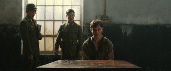 Movie still from “The Railway Man” (2013), directed by Jonathan Teplitzky – A man sitting at a table with a man standing next to him; Medium shot, Over the shoulder angle