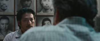 Movie still from “The Railway Man” (2013), directed by Jonathan Teplitzky – Two men are talking in front of a wall of photos; Close Up shot, Over the shoulder angle
