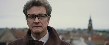 Movie still from “The Railway Man” (2013), directed by Jonathan Teplitzky – A person wearing glasses and a jacket; Close Up shot, Over the shoulder angle