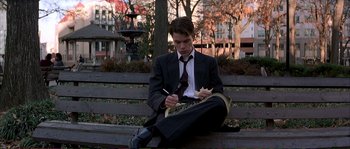 Movie still from “The Rainmaker” (1997), directed by Francis Ford Coppola – A young man sitting on top of a wooden park bench; Medium shot, Low angle