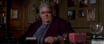 Movie still from “The Rainmaker” (1997), directed by Francis Ford Coppola – An older man sitting at a table in a room; Medium shot, Low angle