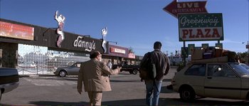 Movie still from “The Rainmaker” (1997), directed by Francis Ford Coppola – Two men walking down the street in front of a building; Wide shot, Over the shoulder angle