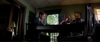 Movie still from “The Rainmaker” (1997), directed by Francis Ford Coppola – A man and a woman sitting at a table in front of a window; Medium shot, Low angle