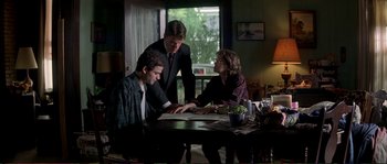 Movie still from “The Rainmaker” (1997), directed by Francis Ford Coppola – Three people sitting at a table looking at a piece of paper; Medium shot, Over the shoulder angle