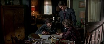 Movie still from “The Rainmaker” (1997), directed by Francis Ford Coppola – Three people sitting at a table looking at papers; Medium shot, High angle