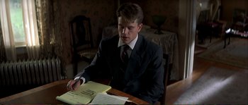 Movie still from “The Rainmaker” (1997), directed by Francis Ford Coppola – A man in a suit and tie writing on a piece of paper; Medium shot, High angle