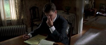Movie still from “The Rainmaker” (1997), directed by Francis Ford Coppola – A young man sitting at a table in front of papers; Medium shot, Over the shoulder angle