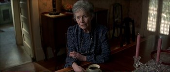 Movie still from “The Rainmaker” (1997), directed by Francis Ford Coppola – An older woman sitting at a table with a cup of coffee in front of her; Close Up shot, High angle