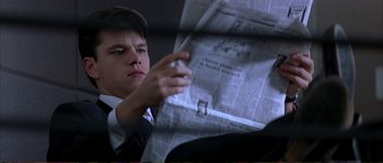 Movie still from “The Rainmaker” (1997), directed by Francis Ford Coppola – A man in a suit and tie holding a cigarette and looking at a newspaper; Close Up shot, Low angle