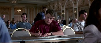 Movie still from “The Rainmaker” (1997), directed by Francis Ford Coppola – A man sitting at a table writing on a piece of paper; Medium shot, Low angle
