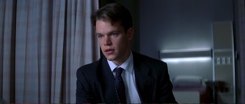 Movie still from “The Rainmaker” (1997), directed by Francis Ford Coppola – A man wearing a suit and tie sitting in a chair; Close Up shot, Low angle