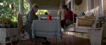 Movie still from “The Rainmaker” (1997), directed by Francis Ford Coppola – A man and a woman sitting at a table on a porch; Wide shot, High angle