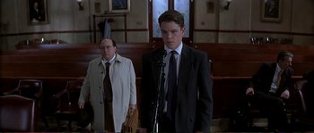Movie still from “The Rainmaker” (1997), directed by Francis Ford Coppola – A man in a suit stands in front of another man in a suit; Medium shot, Low angle