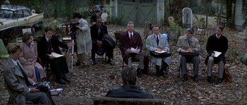 Movie still from “The Rainmaker” (1997), directed by Francis Ford Coppola – A group of men sitting on chairs in the woods; Wide shot, Over the shoulder angle