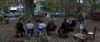 Movie still from “The Rainmaker” (1997), directed by Francis Ford Coppola – A group of people sitting in chairs in a yard; Wide shot, High angle