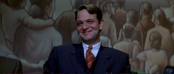 Movie still from “The Rainmaker” (1997), directed by Francis Ford Coppola – A man wearing a suit and tie smiling for the camera; Close Up shot, Low angle